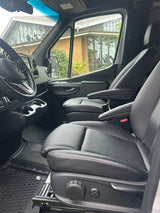 Spacious rv rental interior with black leather adjustable driver/passenger seats, steering wheel, dashboard, and cup holders.