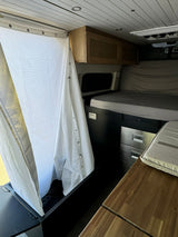 Cozy RV rental interior showing a functional shower, compact bed, Dometic fridge/freezer drawers, and wooden table.