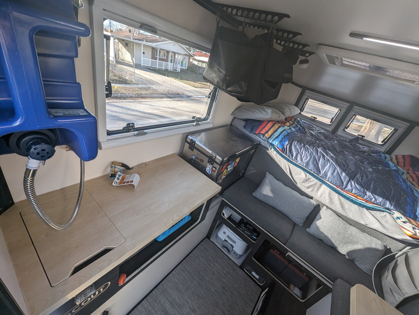 Compact RV rental interior with a cozy bed, seating, kitchen counter, and convenient portable water system. — photo 6