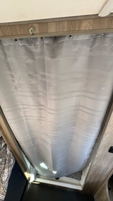 This RV rental's shower features a gray textured curtain with a unique striped pattern and secure top fittings.