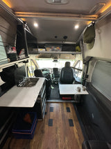 Inside a modern rv rental camper van, showing the compact kitchen with sink, seating area, and cockpit. Perfect for road trips.