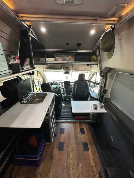 Inside a modern rv rental camper van, showing the compact kitchen with sink, seating area, and cockpit. Perfect for road trips.