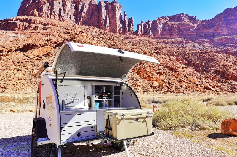 Teardrop RV rental trailer showcasing its compact outdoor kitchen, set against towering red rock cliffs for camping. — photo 11