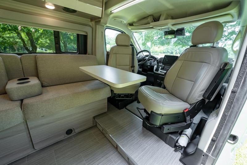 Spacious RV rental interior featuring a dinette with sofa seating and swiveling front seats. — photo 11