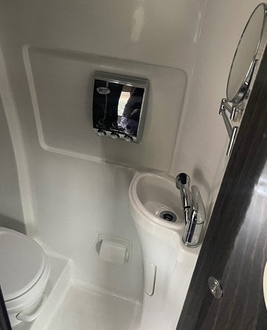  and TV mounted on the wall.|Spacious RV rental interior featuring a modern kitchen with a stove — photo 17