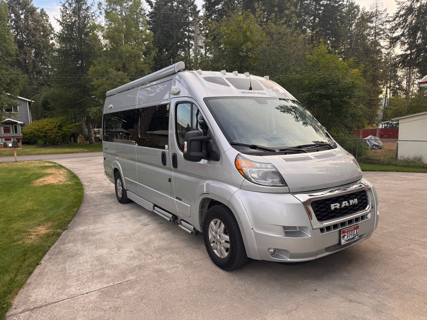 Silver Roadtrek Ram ProMaster rv rental van on a driveway. Perfect camper for adventurous travel.