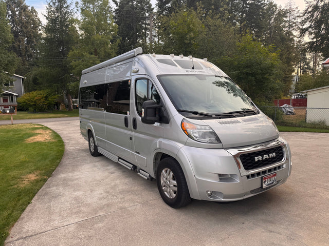 Silver Roadtrek Ram ProMaster rv rental van on a driveway. Perfect camper for adventurous travel.