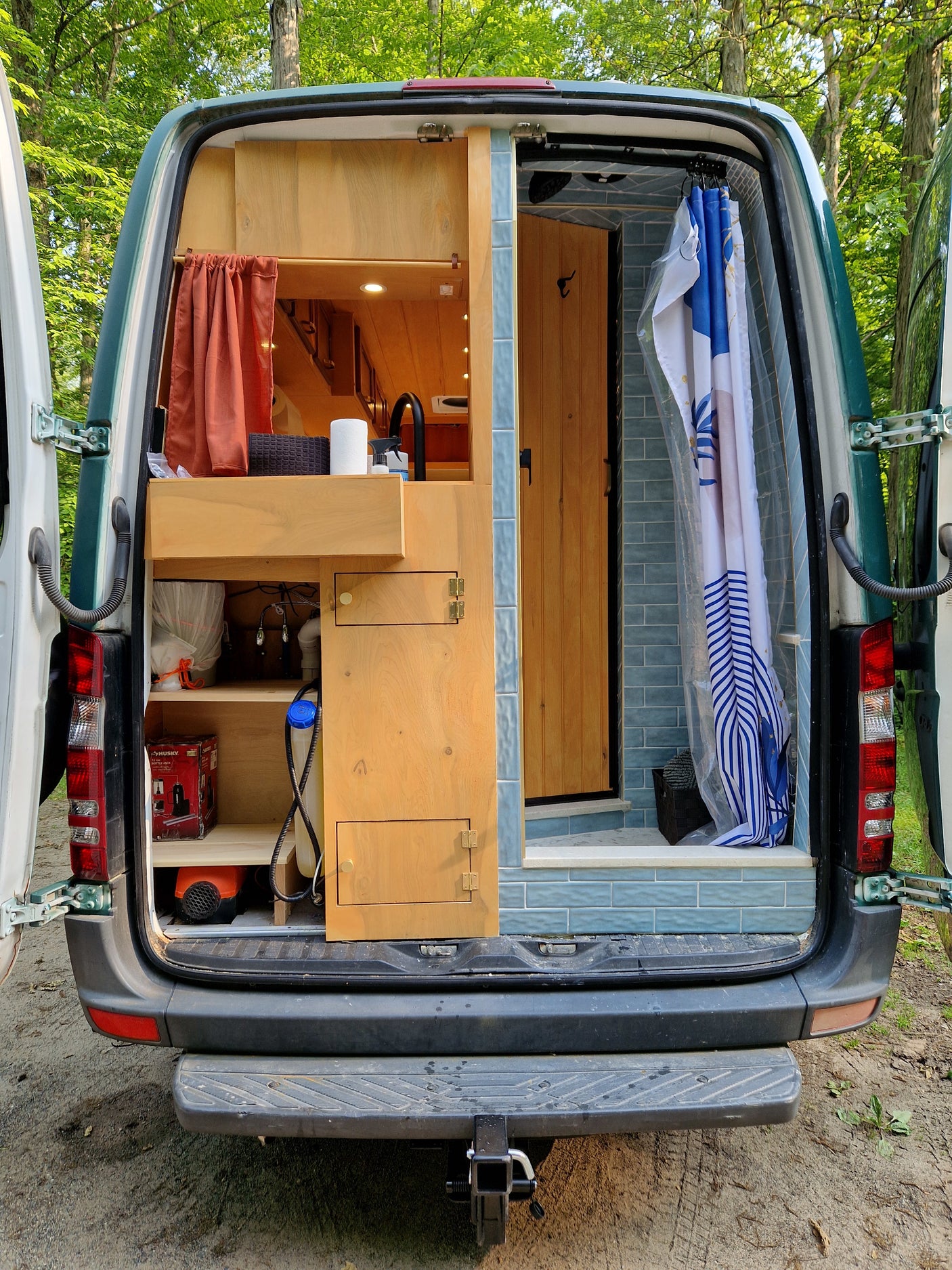 Explore this RV rental's custom camper van conversion! Rear view reveals a compact kitchen, shower, and storage.