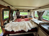 Cozy RV rental interior with a comfy bed, functional kitchen, and scenic window views for travel.