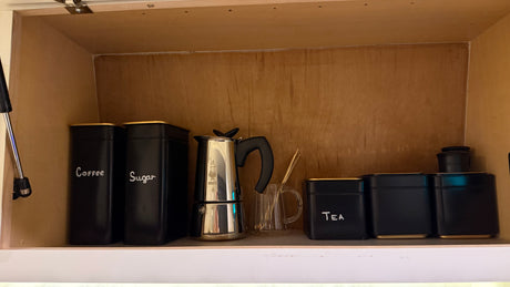 Compact kitchen storage for your RV rental: Coffee, sugar, tea, and a moka pot organized neatly in a cabinet.