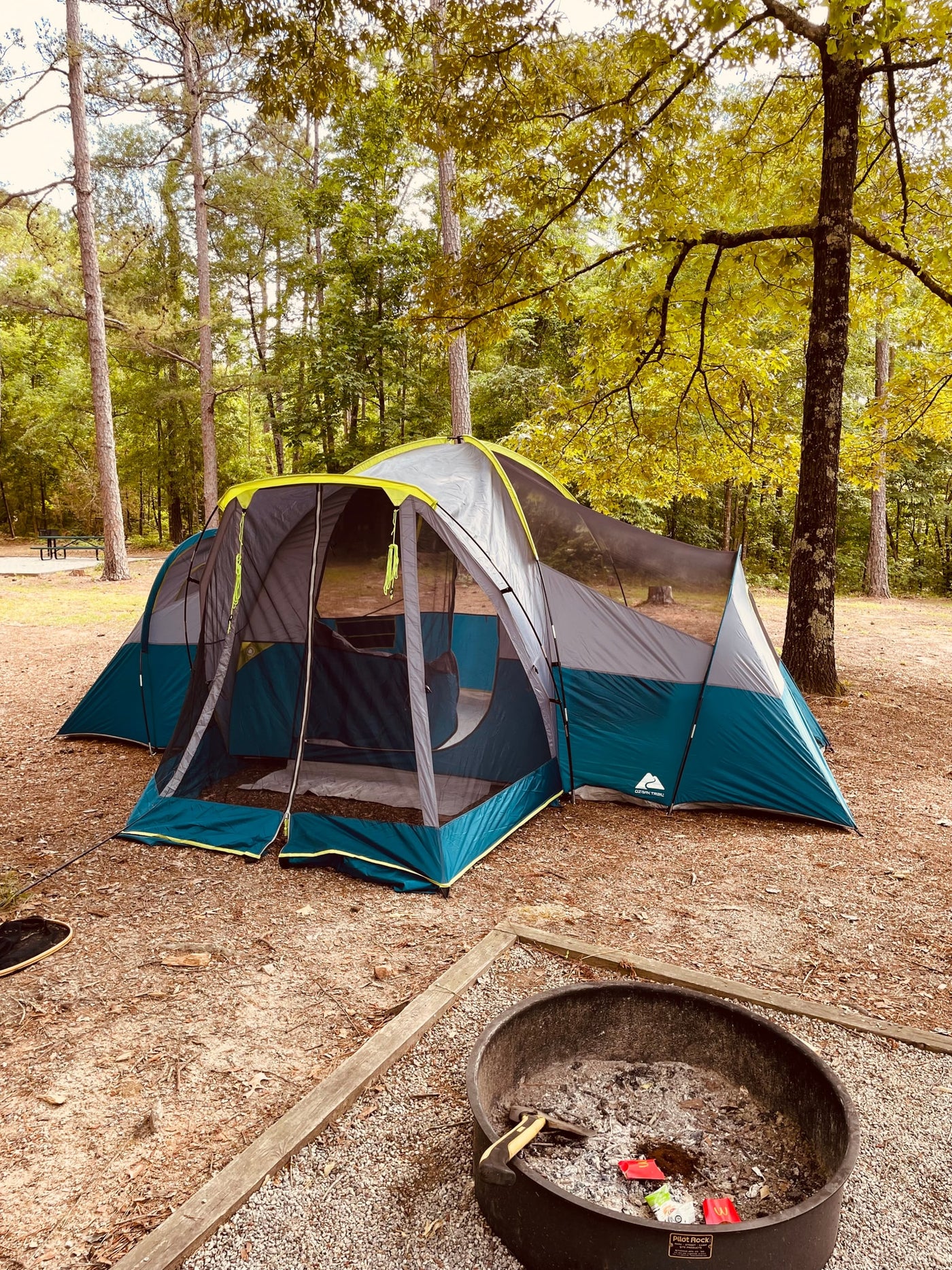 Enjoy nature's embrace: a large tent set up at a wooded campsite, with a fire pit nearby. A relaxing RV rental alternative. — photo 16