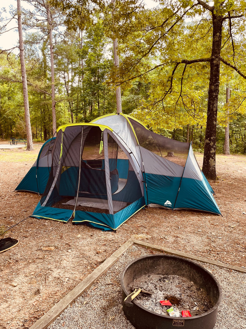Enjoy nature's embrace: a large tent set up at a wooded campsite, with a fire pit nearby. A relaxing RV rental alternative. — photo 16