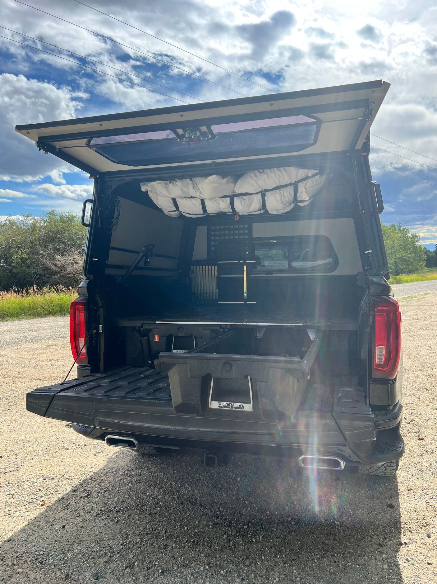 Overland truck with open camper shell reveals organized storage, ready for adventure. A versatile option beyond a typical RV rental for off-grid trips.