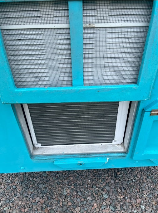 Teal **rv rental** exterior: screened louvered vent and lower cooling fins, parked on gravel.
