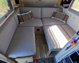 Cozy grey U-shaped dinette in an RV rental, ready for adventure. Comfortable seating & sunlight fill this camper interior.