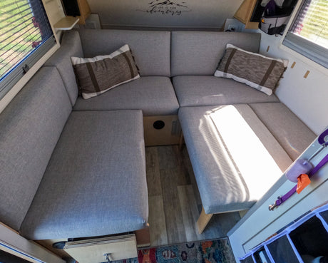 Cozy grey U-shaped dinette in an RV rental, ready for adventure. Comfortable seating & sunlight fill this camper interior.