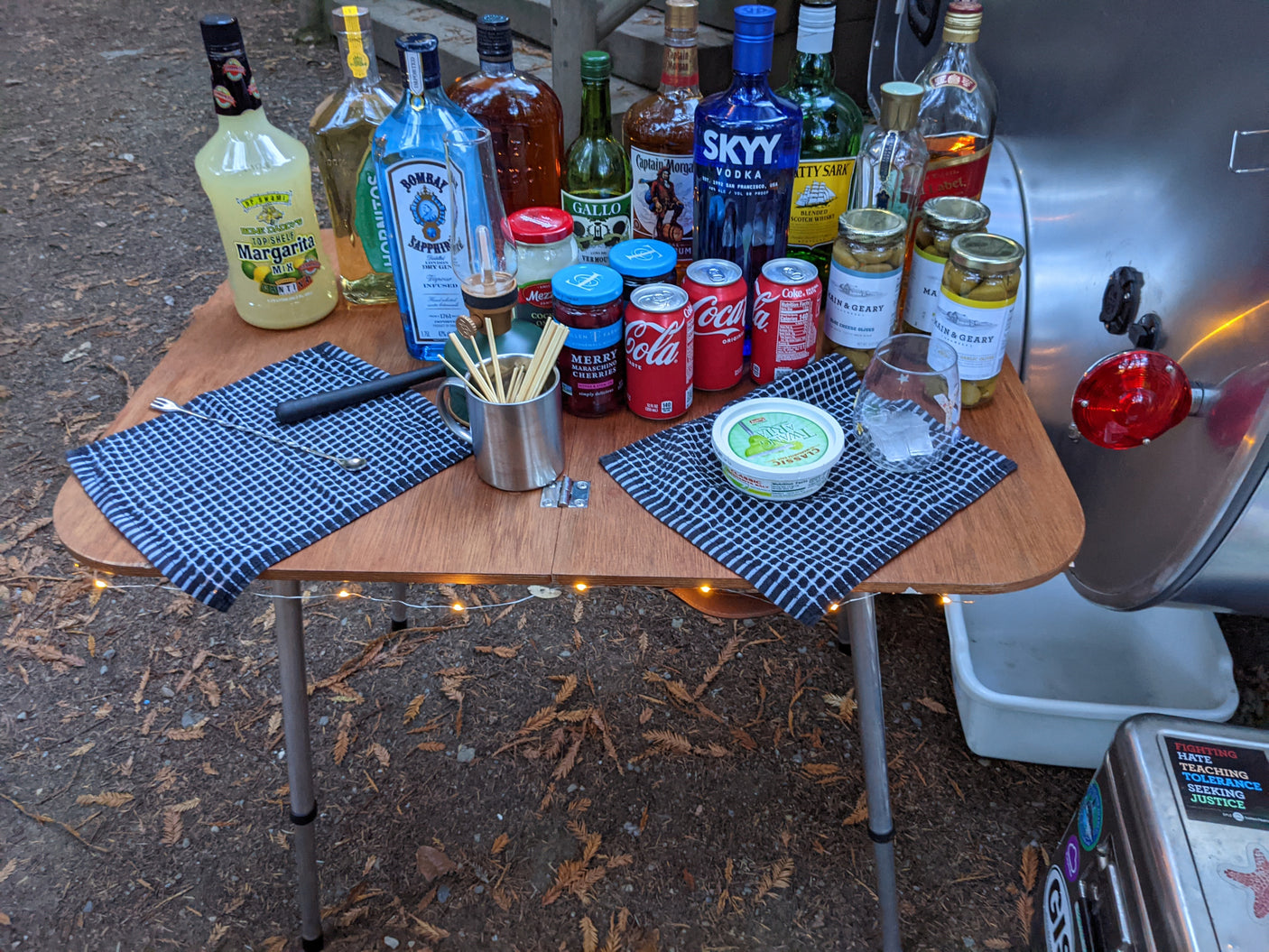 RV rental camping setup: outdoor bar with various spirits, mixers, garnishes, and cocktail tools on a portable table.
