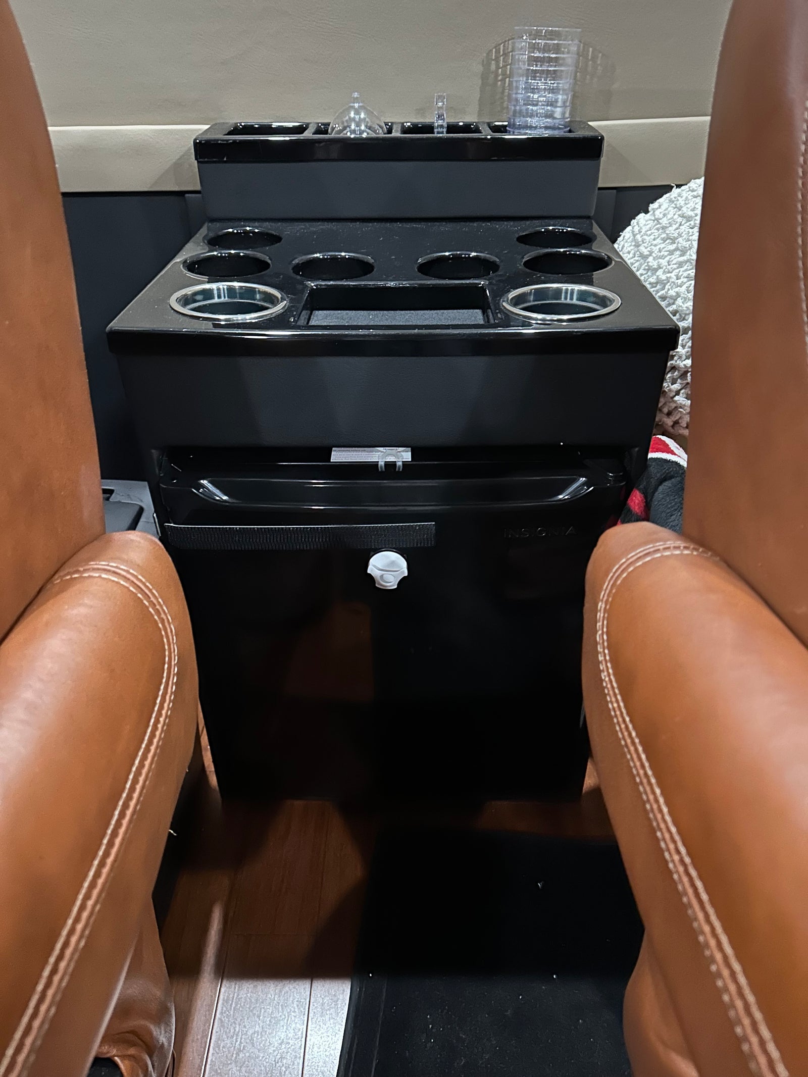 RV rental: Plush leather seats flank a black console with cup holders, storage, and a mini-fridge for ultimate comfort.