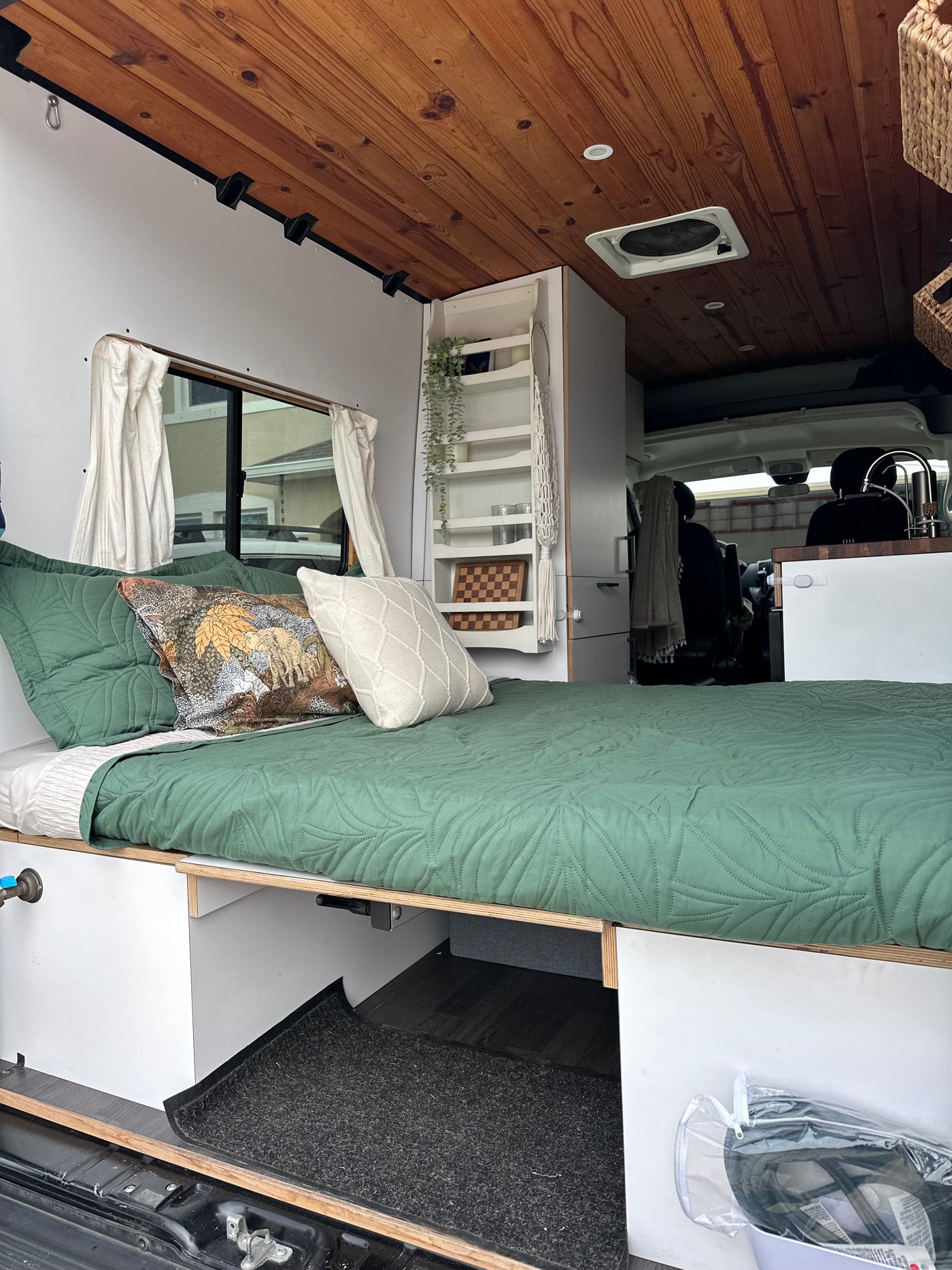 A comfortable RV rental interior with a green quilted bed, warm wood ceiling, and clever built-in storage for travel. — photo 2