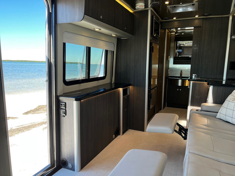 Experience premium RV rental travel with this interior, featuring an open door to a sandy beach & clear water. — photo 1