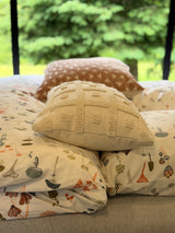 Comfortable RV rental bed with stylish, patterned pillows, offering a serene green nature view outside the window. Enjoy your escape.