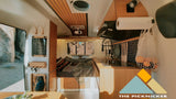 Cozy RV rental interior with a compact wood-paneled kitchen, comfy bed, and clever storage solutions for travel.