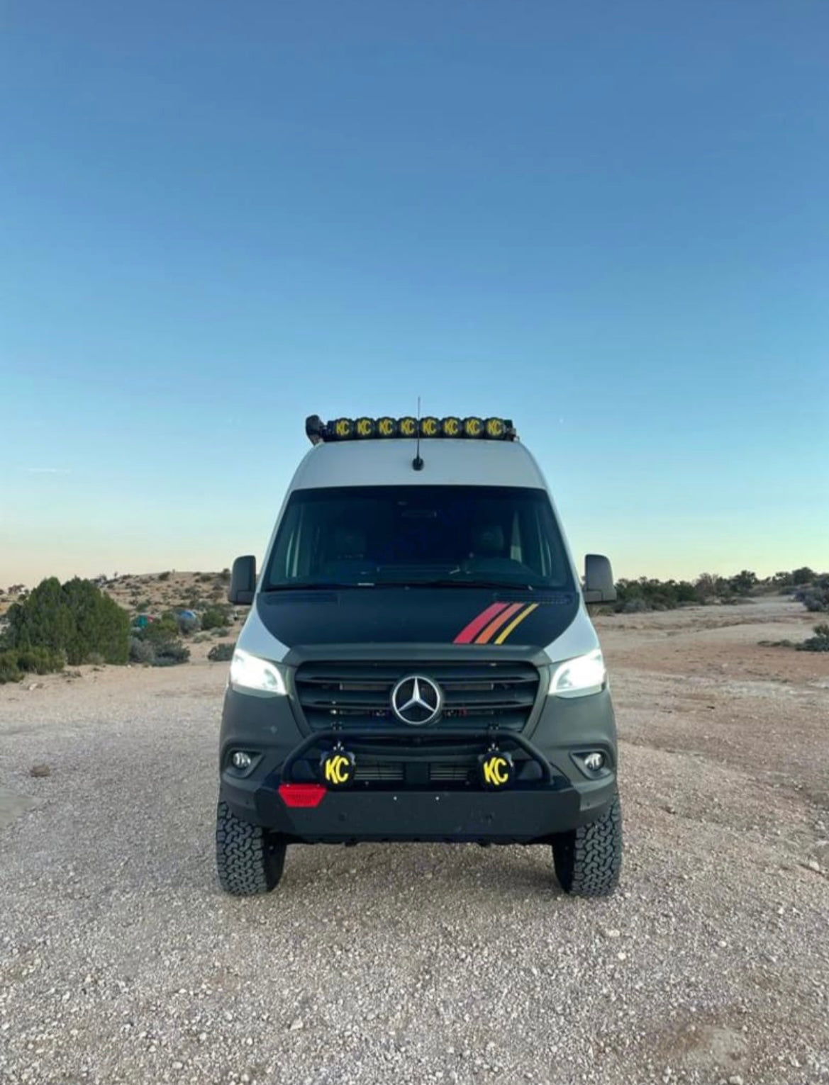Rugged Mercedes Sprinter RV rental, ready for adventure with off-road tires, a bull bar, and roof lights in desert.