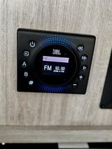 JBL audio control panel in an RV rental, showing FM radio 92.50. Digital display with playback, volume, and zone controls.
