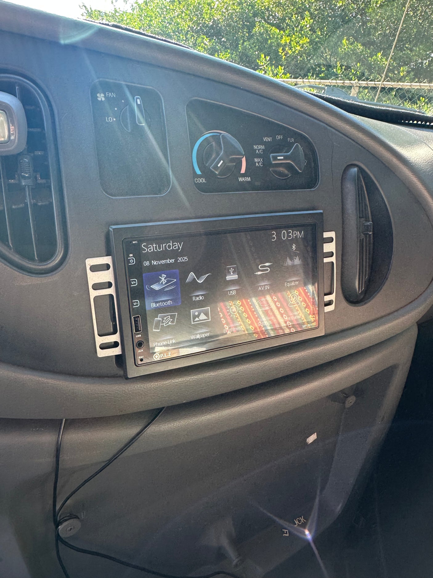 Inside an RV rental: a modern touchscreen car stereo is installed on the dashboard, alongside original HVAC controls. Ready for a road trip.