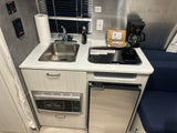 Fully equipped RV rental kitchenette: sink, stovetop, microwave, and mini-fridge. Ready for your adventure.