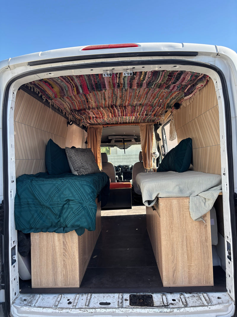 Explore this charming rv rental! A customized camper van interior features two beds, a unique colorful woven ceiling, & wood details. — photo 8