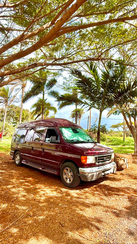 Maroon Ford van, perfect for your next RV rental & outdoor camping adventures in a tropical setting.