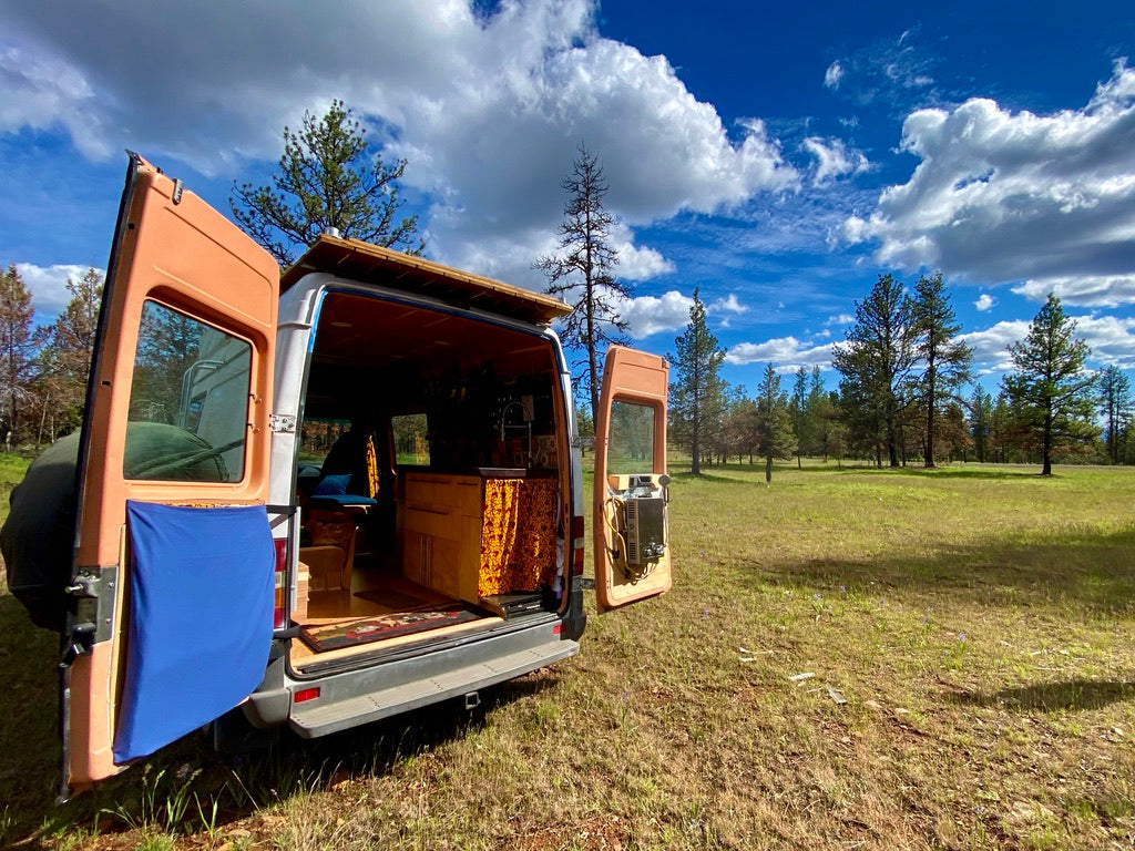 Van life ready! An rv rental parked in a scenic field, revealing its cozy, customized interior. Perfect for adventure!