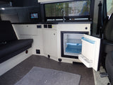 Spacious rv rental interior with a functional kitchen featuring an open fridge, comfy bench seating, and digital controls.