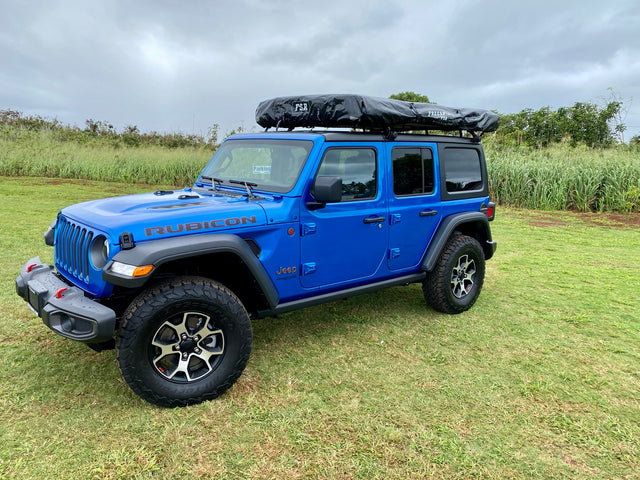This blue Jeep Wrangler Rubicon with a rooftop tent is an ideal RV rental for off-road adventures.