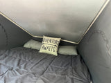 Interior of an RV rental: a comfortable bed with an 'Adventure Awaits' pillow, inviting travel and rest.