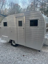 A retro silver travel trailer (camper) on gravel. Ideal for your next RV rental getaway.