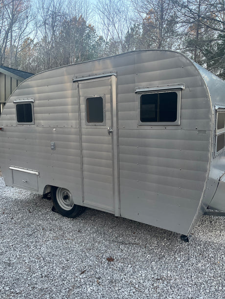 A retro silver travel trailer (camper) on gravel. Ideal for your next RV rental getaway.