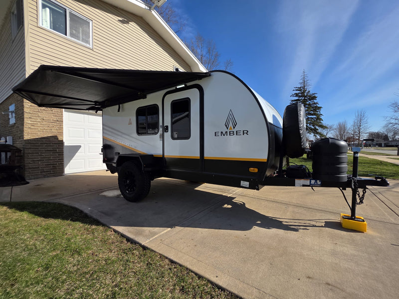 Sleek Ember travel trailer, ready for your RV rental getaway. Parked in a sunny driveway with an extended black awning. — photo 4