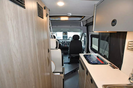 Inside an RV rental, showing the compact living area, kitchenette, and cockpit. Ideal for road trips.