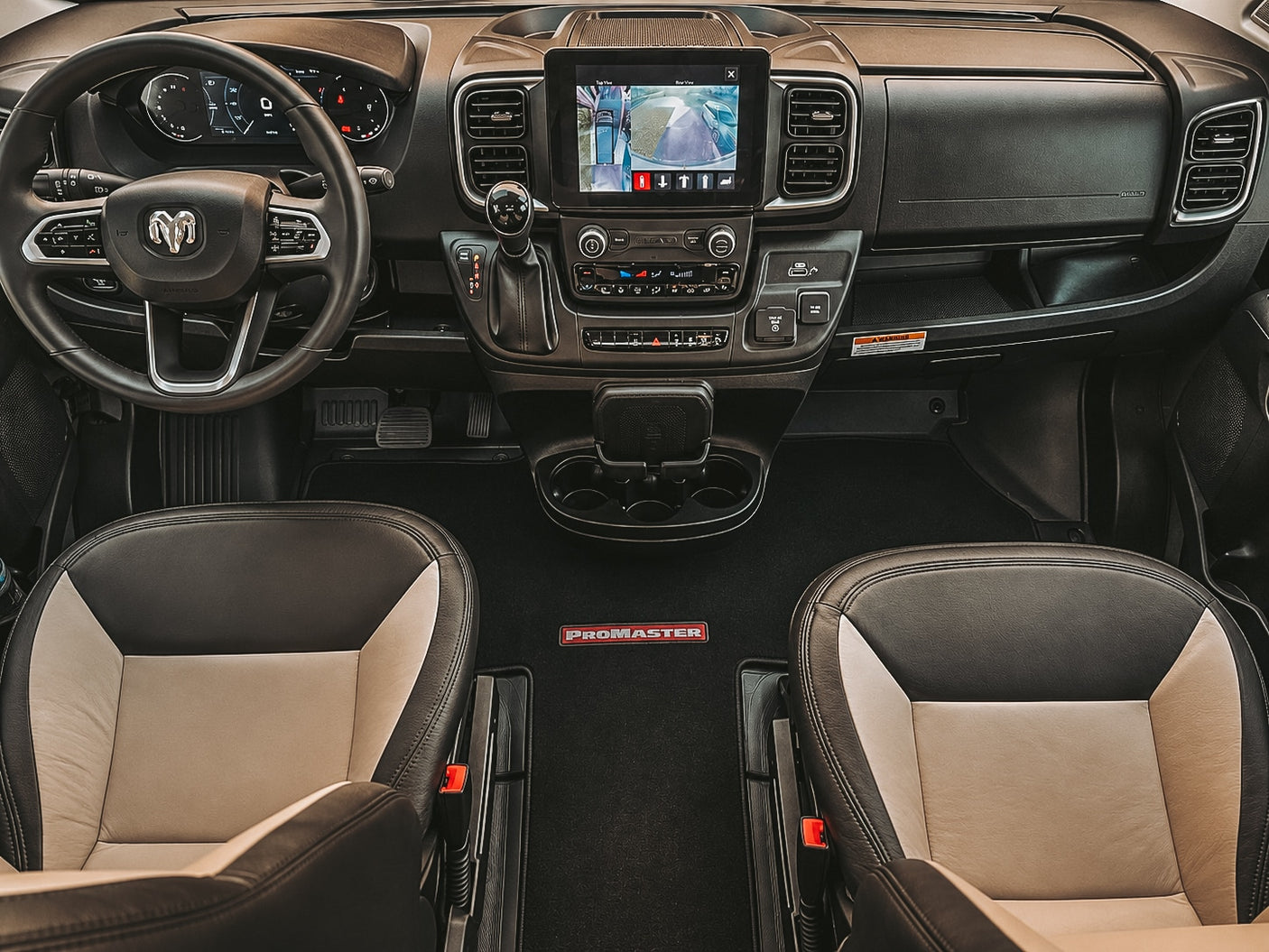 View of a Ram ProMaster RV rental interior, showing the cockpit, dashboard, infotainment screen, and two-tone front seats.
