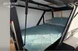 Cozy interior of an rv rental camper: a teal bed, pillows, and an AC unit. Perfect for comfortable mobile lodging.