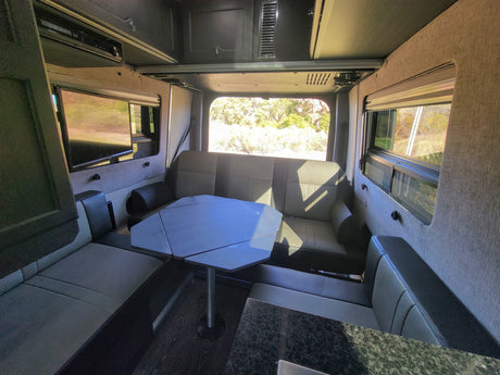 RV rental interior: versatile seating & dining area, entertainment system, and scenic windows for comfortable travel.