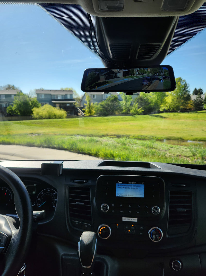 Driver's perspective inside an RV rental. View of dashboard, digital rearview mirror (showing street), and infotainment screen on a sunny day. — photo 6