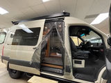 This light-colored adventure camper van, perfect for RV rental, features its side entry open with a bug screen.