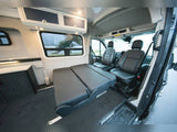 Explore this versatile RV rental camper van interior. Features a convertible bed, cozy front seats, and overhead storage.