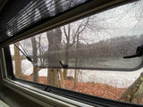 RV rental: Serene rainy day view from inside, featuring a lake, bare trees, and wet window.