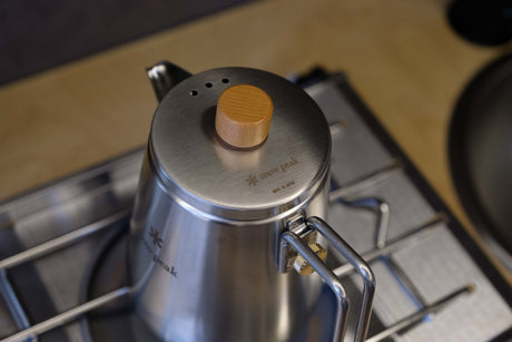 Sleek Snow Peak gooseneck kettle with wooden knob, on a camping stove inside an RV rental. Perfect for travel cooking.
