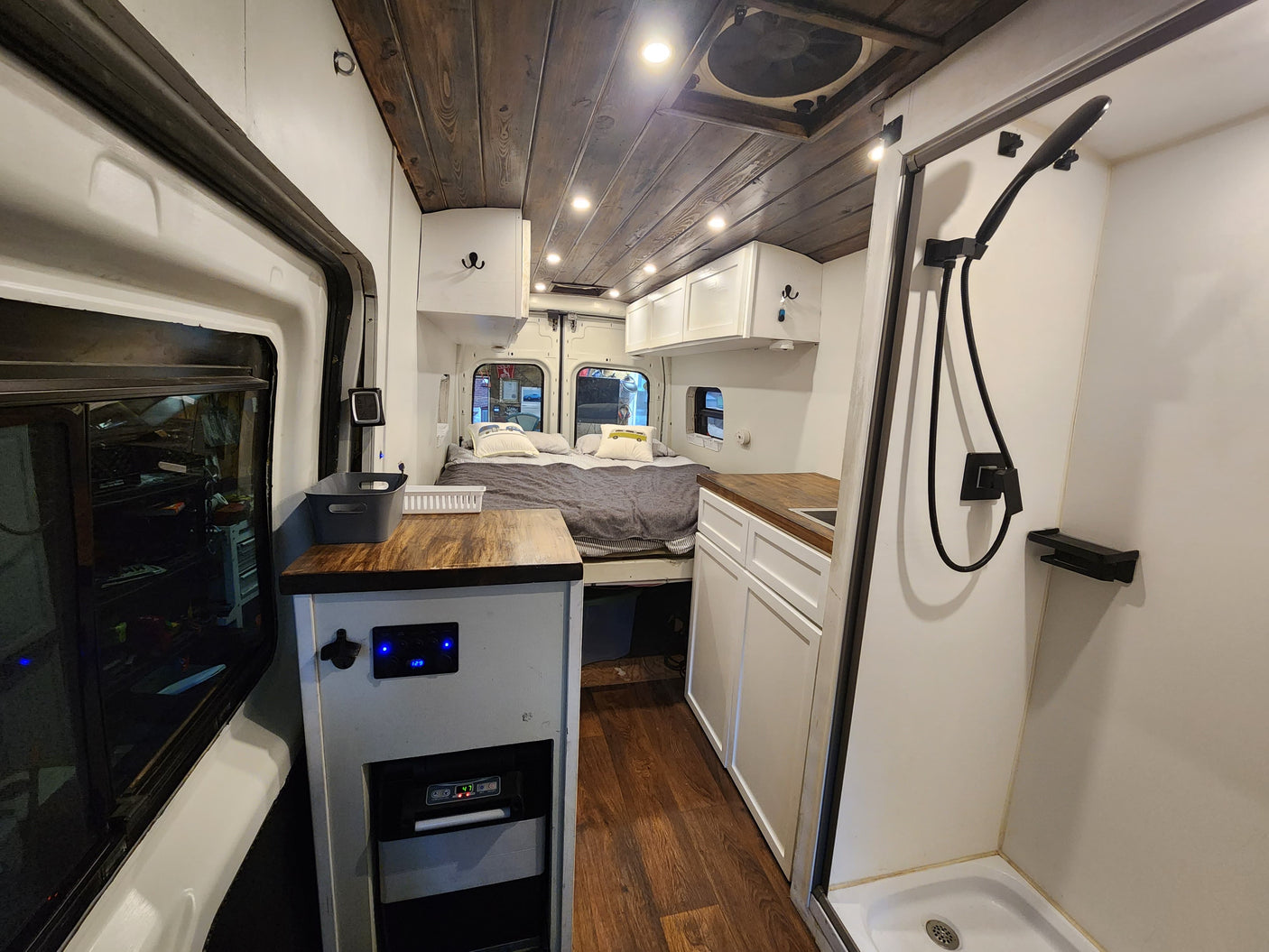 Modern RV rental interior: bed, kitchen, shower, and wood ceiling. Bright, functional camper van for travel.