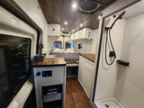 Modern RV rental interior: bed, kitchen, shower, and wood ceiling. Bright, functional camper van for travel.